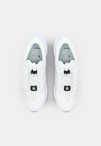 White athletic shoes with a mesh upper, textured laces, and a black toggle closure. Features a cushioned sole and a sleek, curved design.