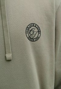 Vaaleanvihreä collegepaita, jossa on teksturoitu kangas ja rintakehällä musta, pyöreä logo "Club Jack & Jones" sekä vuosiluku "Since 1990" ommeltuna.