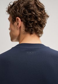 Marineblauer Rundhals-Sweatshirt mit geripptem Kragen, ausgestattet mit einem strukturierten Logo "JOOP! JEANS", das auf dem Rücken eingeprägt ist, glatte Stoffstruktur.