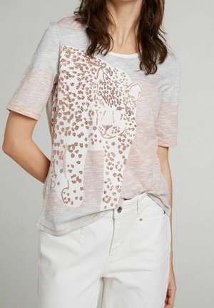 Lysegrå t-shirt med et leoparddesign i metallisk rose guld med detaljer, korte ærmer og en afslappet pasform. Hvide bomuldsbukser vist.