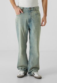 Světle modré džíny z denimu s uvolněným střihem, rovnými nohavicemi a pěti kapsami; mají zip a kovové zapínání na knoflík.