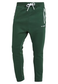 Gröna atletiska joggers med slim fit, tillverkade av mjukt material. Har vit dragsko, sidofickor med dragkedja och logotyp på benet.