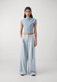 Light blue cropped top with cap sleeves paired with wide-leg light blue trousers featuring a belt and tied detail. Smooth texture overall.