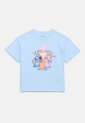 Chemise bleu clair avec des personnages de dessins animés bleus et roses s'enlaçant devant un cornet de glace rose, le texte indique "AMOUR VRAI TOUJOURS".