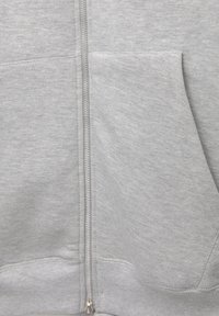 Close-up of light gray zip-up hoodie fabric showing front pocket and zipper details.