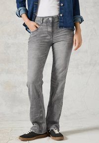 Grijze denim jeans met een slanke, flared pootontwerp, met een klassieke vijf-pocketstijl en subtiele vervaging, gecombineerd met zwarte sneakers.