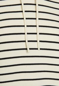 Hoodie typu pulower z kremowym tłem i poziomymi czarnymi pasek. Posiada dwa sznurki z plastikowymi końcówkami. Miękka, prążkowana tekstura.