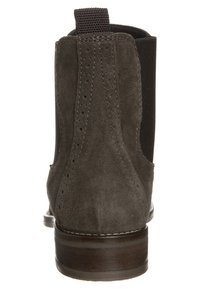 Bottine Chelsea en daim marron vue de dos, avec des détails cousus, un languette de traction, des panneaux latéraux élastiques et un talon en bois empilé.