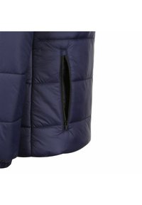 Giacca puffer blu navy con design trapuntato, dotata di tasca laterale con zip. Il tessuto appare liscio e leggermente lucido.