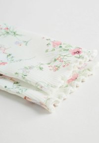 Tela blanca con motivos florales en rosa y verde, con textura acanalada y bordes con volantes. Material suave y ligero.