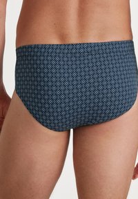 Blaue Schwimmslips mit Diamantmuster, elastischem Bund und glatter Stoffoberfläche. Liegt eng um die Taille und Oberschenkel an.