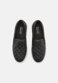 Baskets vegan noires à enfiler avec texture matelassée, panneaux latéraux élastiques et semelle en caoutchouc blanche. Conçues pour un port facile et un confort optimal.