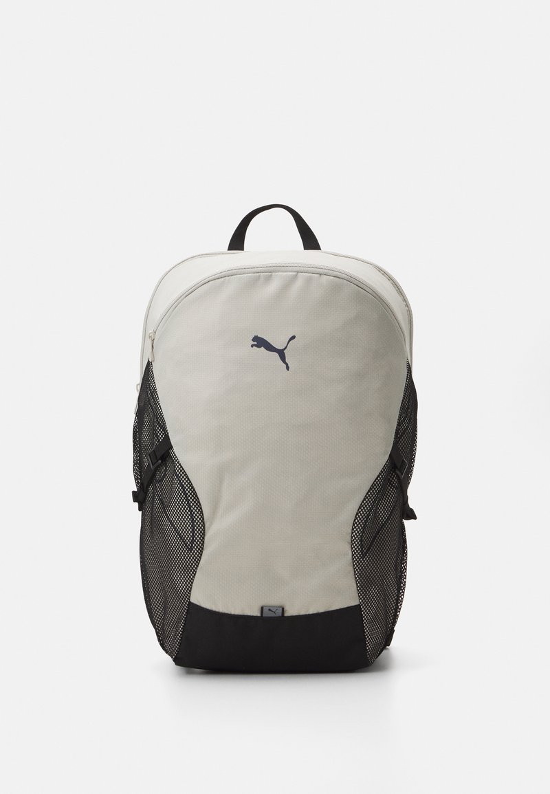 Sac à dos gris et noir avec des poches latérales en mesh, au design courbé, et un logo noir Puma bien visible sur le devant. Fermeture éclair en haut.