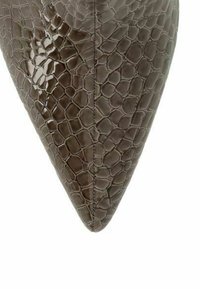 Close-up of pointed toe brown leather shoe with embossed reptile skin texture and central stitching.