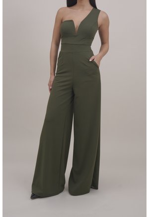 Kombinezon w oliwkowej zieleni z głębokim dekoltem w kształcie litery V i asymetrycznym jednym ramieniem, wyposażony w spodnie o szerokich nogawkach oraz boczne kieszenie. Wykonany z gładkiej, elastycznej tkaniny.