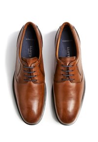 Braune Lederschuhe mit glattem Finish, Schnürdesign und kontrastierender schwarzer Sohle. Enthält dezente perforierte Details.