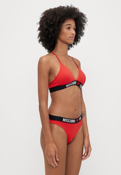 Costum de baie roșu format dintr-un top triunghiular și chiloți de bikini cu un bandou negru contrastant, pe care este inscripționat textul "MOSCHINO" și "YOU". Textură netedă.