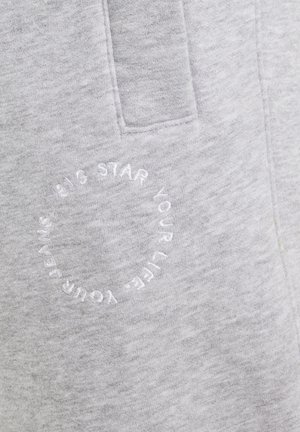 Světlě šedá látka s našitou kapsou a kruhovým bílým vyšitým nápisem „BIG STAR YOUR LIFE YOUR FRIENDS“.