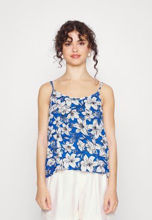 Top de alças spaghetti floral com um fundo azul e flores brancas, ajuste solto e tecido leve. Calções brancos simples.