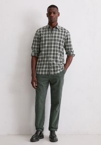 Groen geruit overhemd met opgerolde mouwen, gecombineerd met donkergroene corduroy broek en zwarte veterschoenen. Eenvoudige en slim fit.
