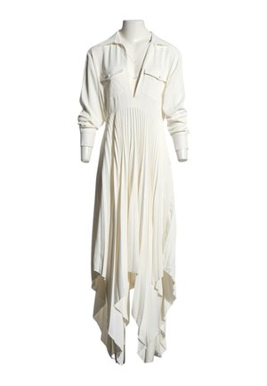 Longue robe blanche avec une jupe plissée, des manches longues, deux poches poitrine et un ourlet asymétrique sur un mannequin.