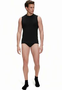 Black sleeveless tank top and black brief displayed on a model, showcasing a fitted design and smooth texture against a neutral background.