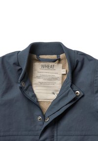 Navyblauwe jas met een zachte beige fleece voering, geribbelde kraag, drukknoopsluiting en een genaaide verzorgingslabel. Bevat gerecycled materiaal.