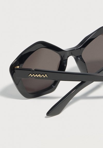 Black oversized square sunglasses with dark lenses and gold "Marni" logo on the temple arm on a light background.