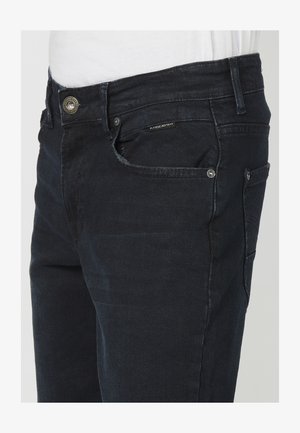 Jeans din denim închis la culoare, cu un design cu picior drept, având închidere cu buton, buzunare frontale și dorsale, și o etichetă de marcă subtilă.