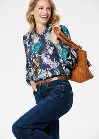 Blusa floreale navy con motivi verdi, viola e arancioni; jeans blu; borsa in pelle marrone; vestibilità comoda; dettagli in tessuto testurizzato.