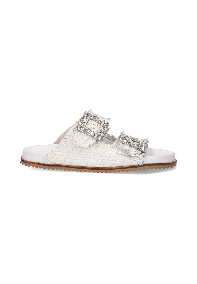 Sandalias de slide blancas trenzadas con dos hebillas decorativas que presentan gemas transparentes, parte superior texturizada y una suela de goma marrón en contraste.