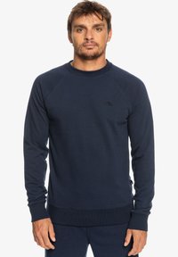 Navy blue sweatshirt in a soft, cotton blend. Features long sleeves, a crew neck, ribbed cuffs, and a small logo on the chest.