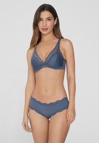 Modrý krajkový podprsenka s trojúhelníkovým vzorem a vlnitými okraji, doplněná o odpovídající brazilské kalhotky s krajkovým lemem. Hladká textilie.
