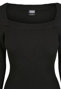 Top noir à manches longues côtelé avec un col carré. Tissu élastique et coupe ajustée mettent en valeur la silhouette, avec une étiquette de marque à l'intérieur.