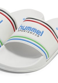 Des sandales glissantes blanches avec une large sangle portant le texte "Hummel Sportswear" en bleu et trois bandes d'accent en rouge, vert et bleu. Semelle texturée.