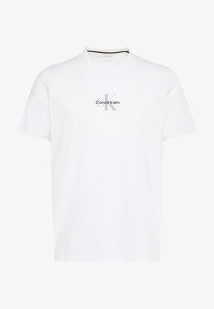 Valkoinen lyhythihainen pusero pyöreällä kaula-aukolla, jossa rinnassa on keskitettynä harmaa ja musta teksti "cK"-alkuisilla nimikirjaimilla ja "Calvin Klein".