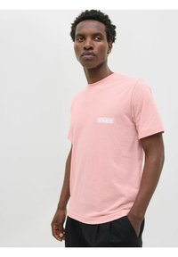 Lyserød bomulds t-shirt med rund hals, korte ærmer og lille hvidt logo på venstre bryst. Glat tekstur, afslappet pasform.
