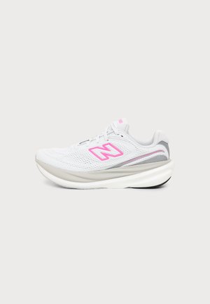 Λευκό αθλητικό παπούτσι New Balance με ρόζ λογότυπο, γκρι λεπτομέρειες και παχύ μαλακό πάτο, εμφανιζόμενο από το πλάι σε απλό φόντο.