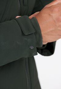 Mørkegrøn jakkeærme med en glat tekstur, sikker trykknaplukning og håndledskantdesign med en elastisk band.