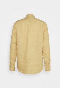 Chemise en lin beige à manches longues, vue de dos, avec poignets boutonnés et coupe droite sur fond uni.