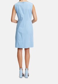 Jasnoniebieska sukienka bez rękawów o prostym kroju, z zamkiem błyskawicznym z tyłu. Zestawiona z dopasowanymi sandałami na słupku.