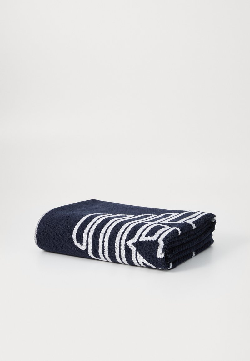 Navy blue towel with white striped pattern, soft texture, folded neatly to display design. Cotton material, rectangular shape.