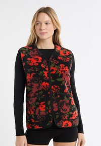 Kwiatowa kamizelka z polaru na czarnym tle, z czerwono-zielonymi wzorami, zapinana na zamek błyskawiczny, z przednimi kieszeniami. Tkanina o teksturze.