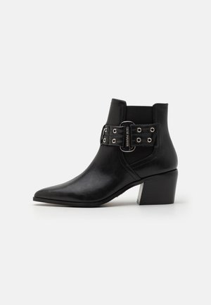 Black leather ankle boots with a pointed toe, elastic side panel, and decorative buckle strap featuring metal eyelets. Block heel.