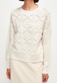 Maglione lavorato a maglia in off-white con motivi a diamante testurizzati. Presenta polsini a coste e un collo rotondo, realizzato con un tessuto morbido e leggero.