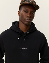 Felpa nera realizzata in morbido cotone, caratterizzata da una tasca a marsupio frontale, cappuccio regolabile con coulisse e la scritta "LES DEUX" ricamata in bianco sul petto.