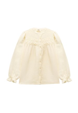 Camisa de botones color crema con largas mangas abullonadas, detalles fruncidos y puños con volantes. Fabricada con una tela ligera y texturizada.