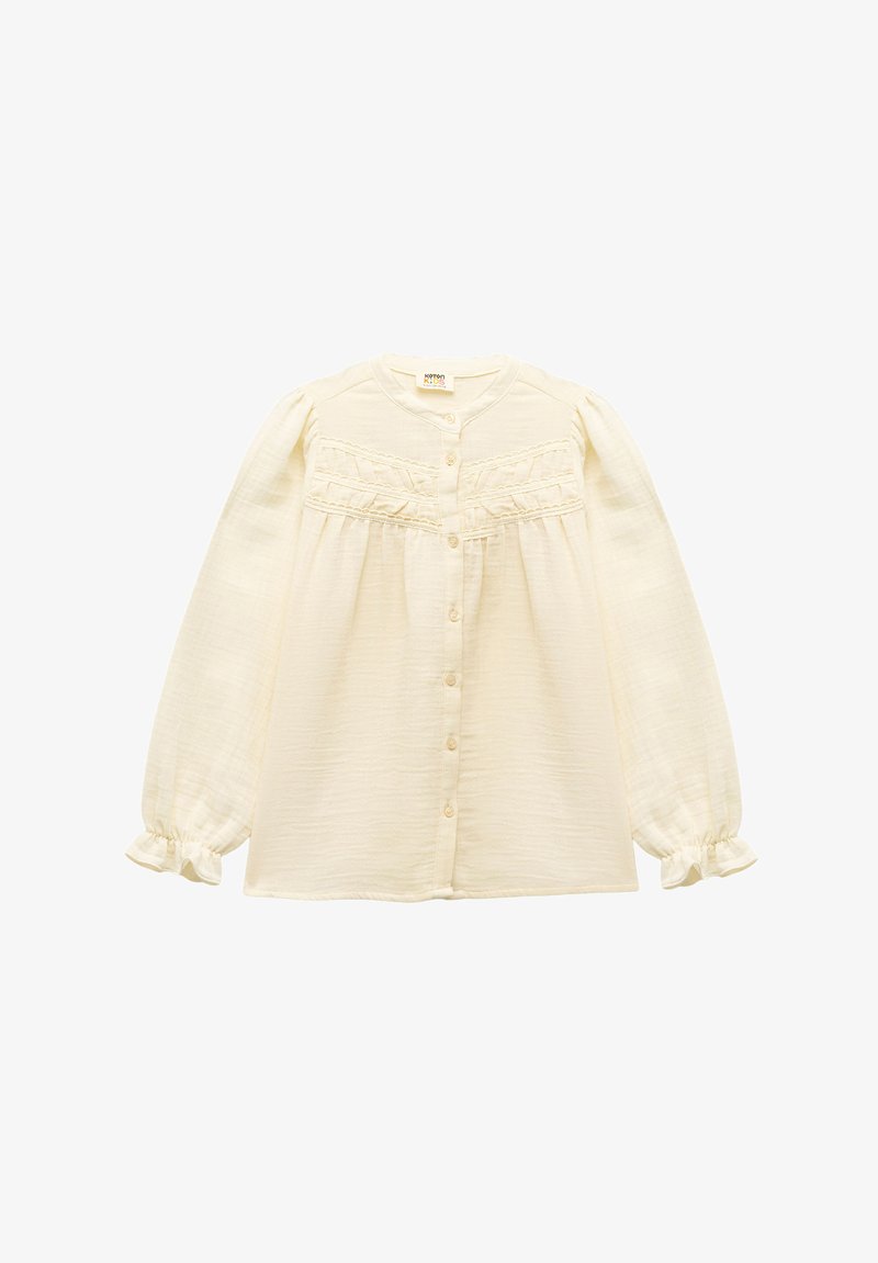 Cremfarbener Hemd mit langen, gepufften Ärmeln, gerafften Details und Rüschenmanschetten. Hergestellt aus leichtem, strukturiertem Stoff.