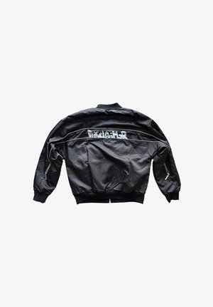 Giacca bomber nera in tessuto liscio, con colletto e polsini a coste, tasche con cerniera e scritta bianca sul retro.