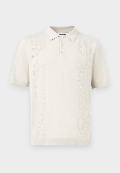 Κρεμ πόλο πουκάμισο με κοντά μανίκια, τρία κουμπιά και διακριτικές κάθετες διάτρητες ρίγες στο μπροστινό μέρος.